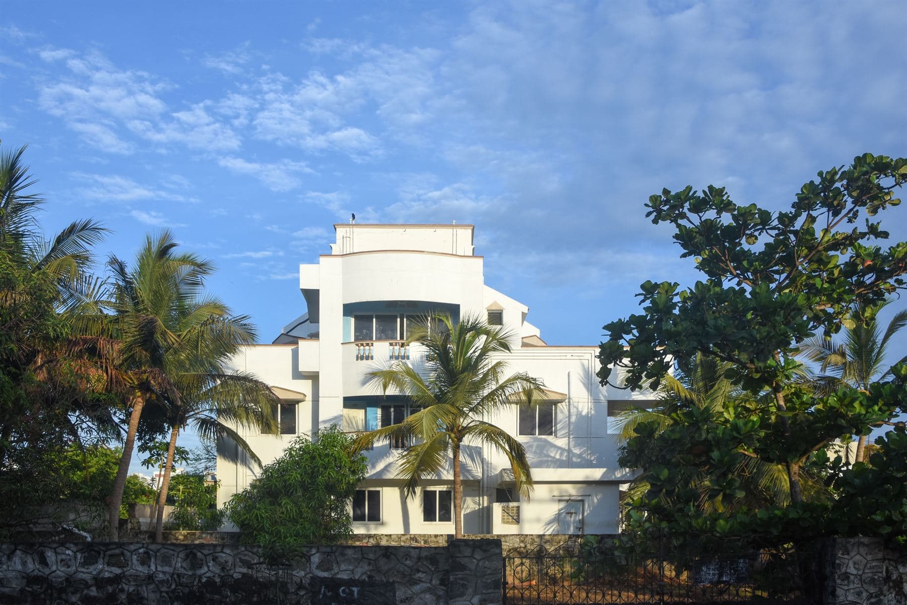 White independent house framed by coconut palms